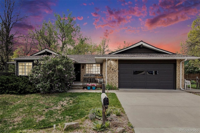 ranch-style home featuring brick siding, concrete driveway, a garage, a front yard, and a shingled roof