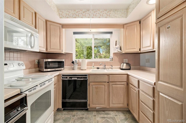 kitchen with white appliances, light brown cabinetry, light countertops, and a sink
