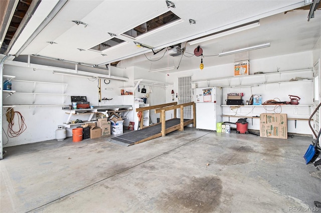 garage featuring freestanding refrigerator, a workshop area, and a garage door opener