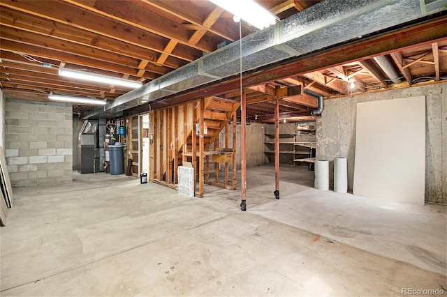 unfinished basement with heating unit, strapped water heater, and stairway