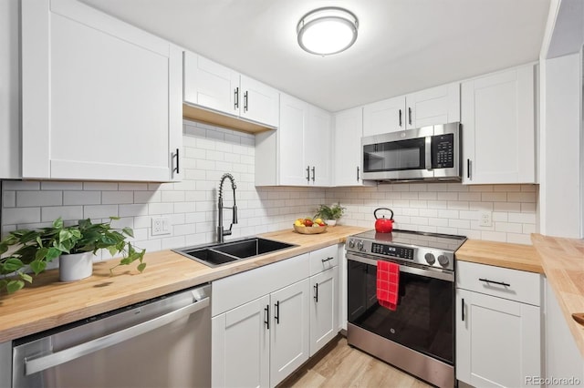 9700 E Iliff Ave Unit A3, Denver, CO 80231 - kitchen featuring stainless steel appliances, wooden counters, white cabinets, tasteful backsplash, and light wood-type flooring