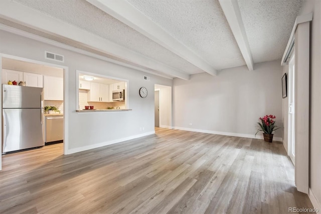 9700 E Iliff Ave Unit A3, Denver, CO 80231 - unfurnished living room with beamed ceiling, light wood-style flooring, and a textured ceiling