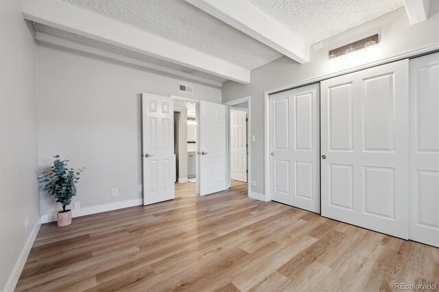 9700 E Iliff Ave Unit A3, Denver, CO 80231 - unfurnished bedroom featuring beam ceiling, a textured ceiling, light wood-type flooring, and a closet