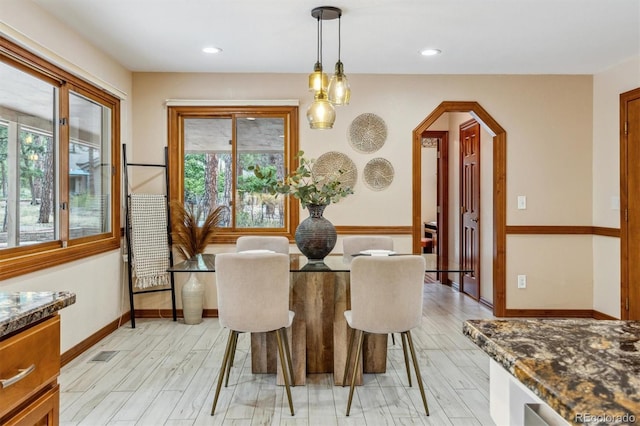 dining room with arched walkways, light wood-type flooring, baseboards, and recessed lighting