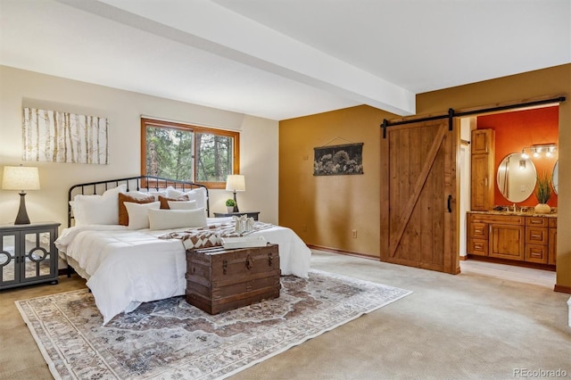 bedroom featuring a barn door, beamed ceiling, light carpet, and connected bathroom