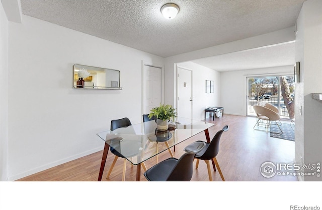 dining room featuring a textured ceiling, wood finished floors, and baseboards