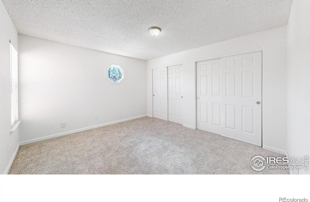 unfurnished bedroom featuring a textured ceiling, baseboards, and carpet flooring