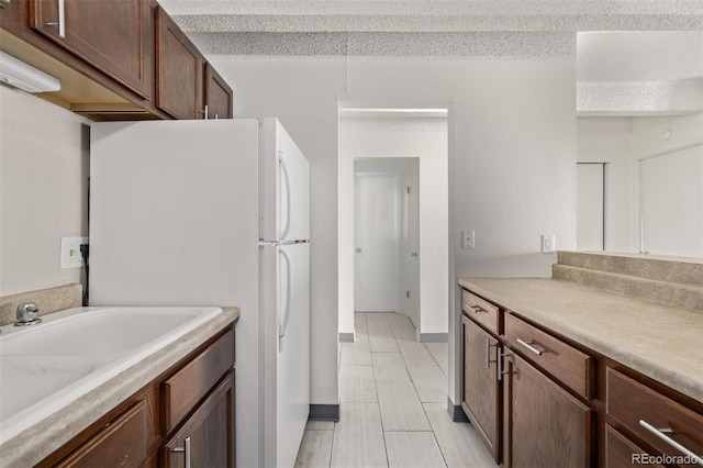 kitchen with sink, a textured ceiling, and white refrigerator