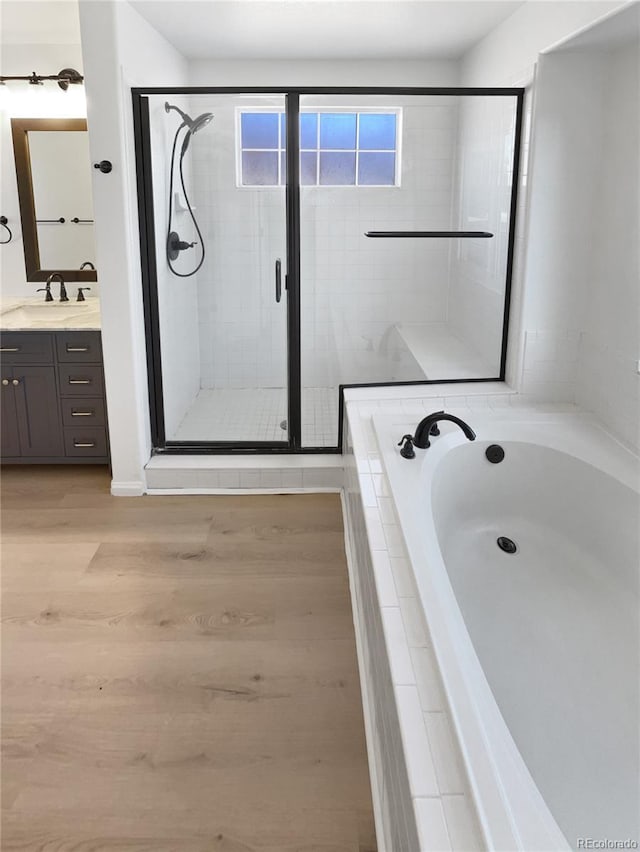 4735 S Cathay Ct, Aurora, CO 80015 - bathroom with vanity, a bath, a stall shower, and wood finished floors
