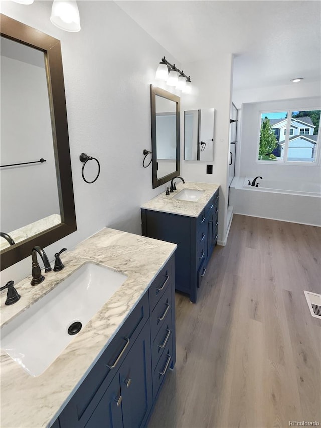 4735 S Cathay Ct, Aurora, CO 80015 - bathroom featuring two vanities, wood finished floors, and a garden tub