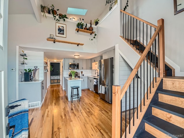 interior space featuring a skylight, wood finished floors, visible vents, and a towering ceiling