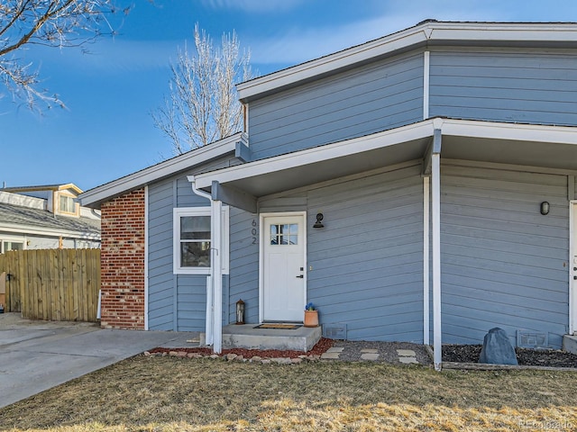 entrance to property featuring brick siding and fence