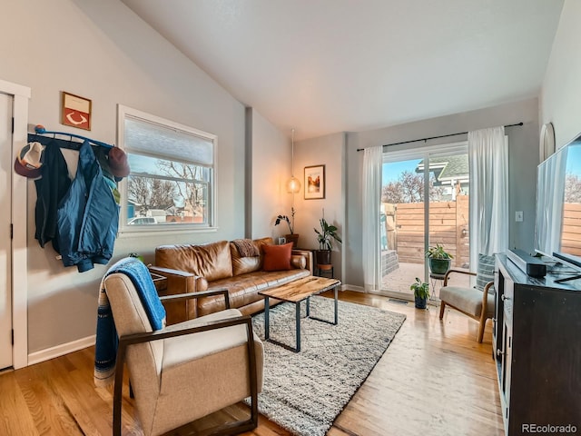 living room with light wood-style flooring, baseboards, and lofted ceiling