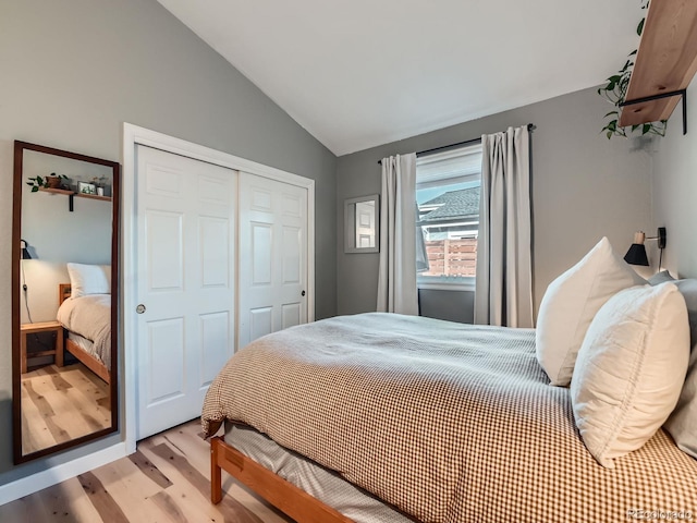 bedroom featuring a closet, wood finished floors, and vaulted ceiling