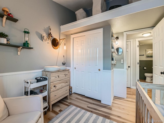 interior space with a closet, light wood-style floors, and wainscoting