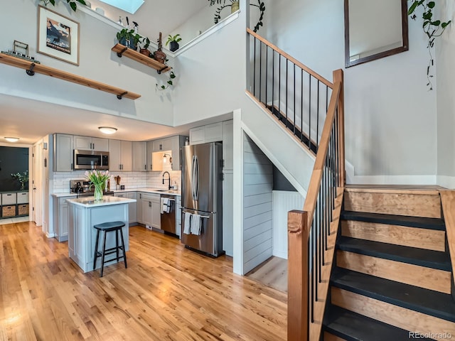 kitchen with gray cabinetry, a sink, a center island, stainless steel appliances, and light countertops