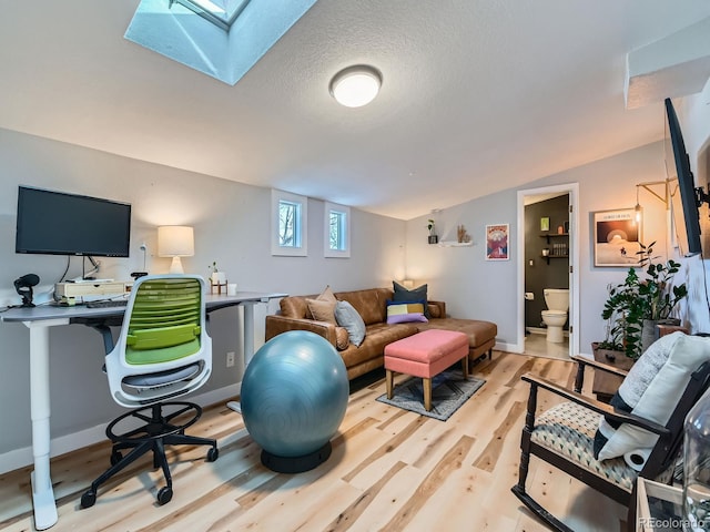 living room featuring vaulted ceiling, wood finished floors, baseboards, and a textured ceiling