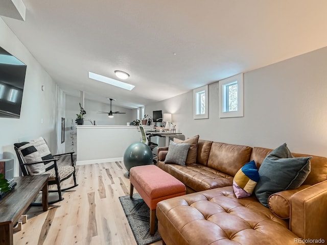 living area featuring vaulted ceiling with skylight and light wood finished floors