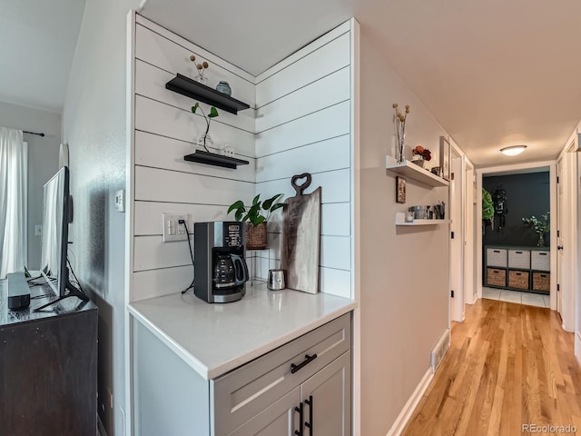 hall with light wood finished floors, visible vents, and baseboards