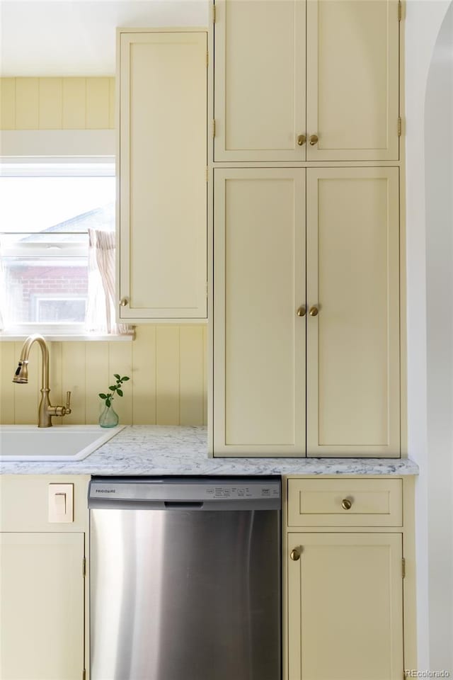 kitchen featuring stainless steel dishwasher, sink, and cream cabinetry