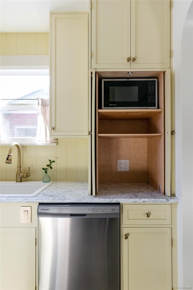 kitchen featuring built in microwave, stainless steel dishwasher, sink, and cream cabinetry