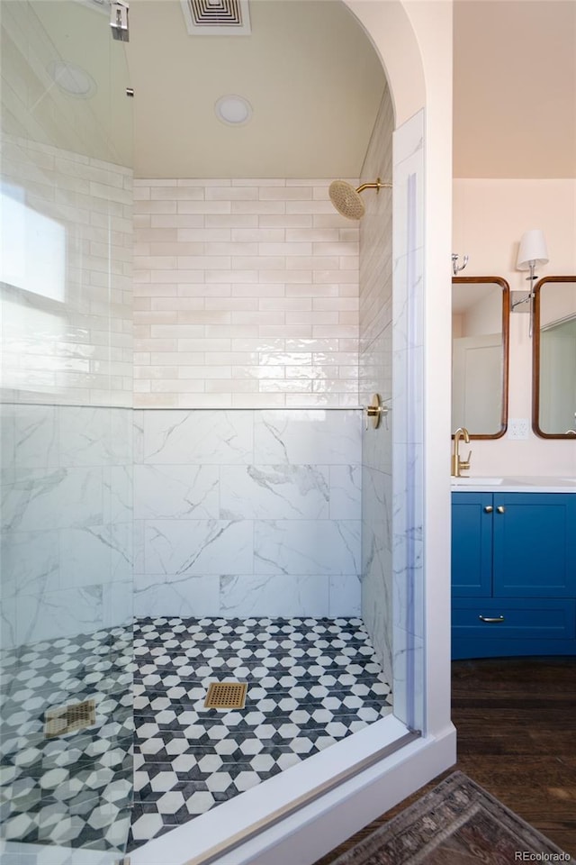 bathroom featuring wood-type flooring, a shower with shower door, and vanity