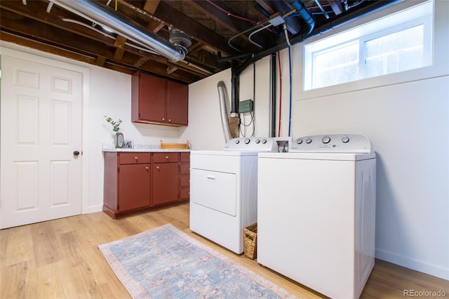 washroom with cabinets, washer and dryer, and light wood-type flooring