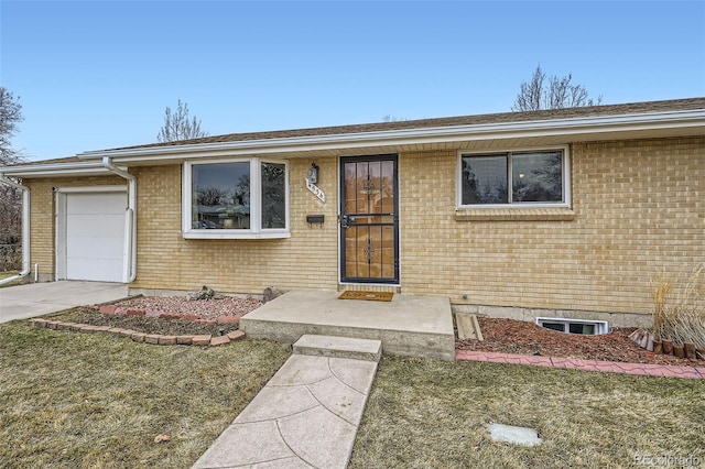 view of front of property featuring an attached garage, driveway, a front lawn, and brick siding