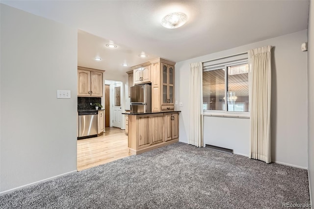 kitchen with light colored carpet, appliances with stainless steel finishes, decorative backsplash, dark countertops, and glass insert cabinets