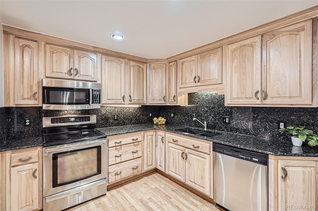 kitchen featuring stainless steel appliances, a sink, and light brown cabinetry