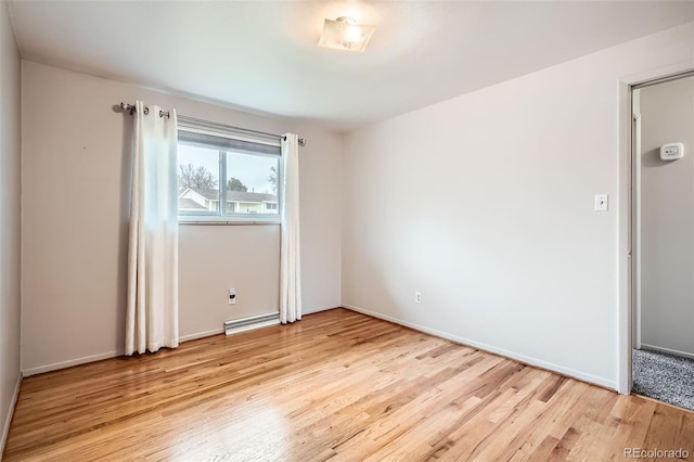 spare room with light wood-style floors, baseboards, and a baseboard heating unit