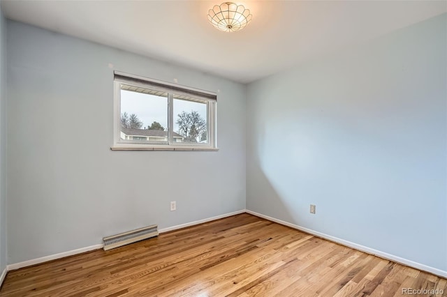 spare room featuring wood finished floors, visible vents, and baseboards