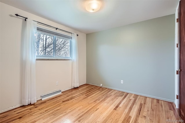 spare room featuring light wood-type flooring, visible vents, and baseboards