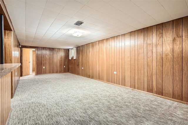 unfurnished room featuring carpet flooring and wood walls