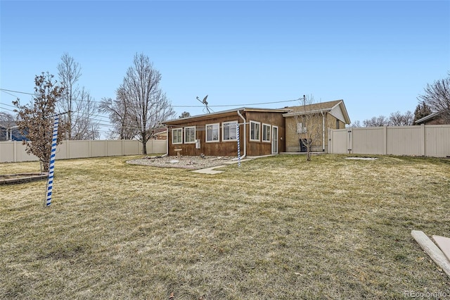 rear view of property featuring a gate, a fenced backyard, and a yard