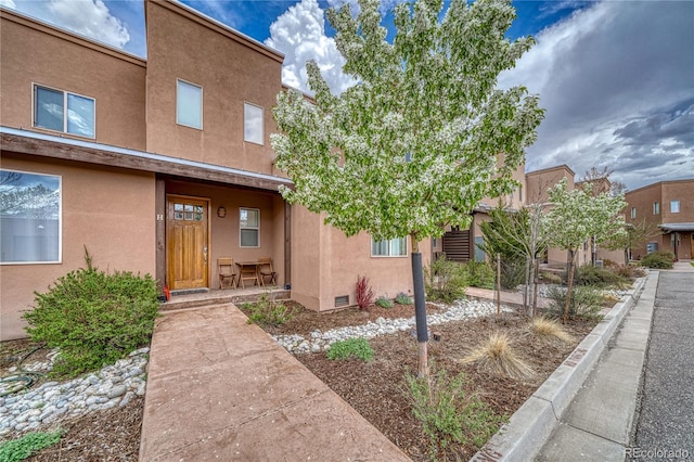 view of front facade with crawl space, stucco siding, and covered porch