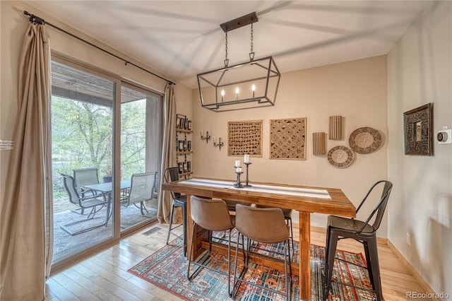 dining area featuring light wood finished floors, a chandelier, and baseboards