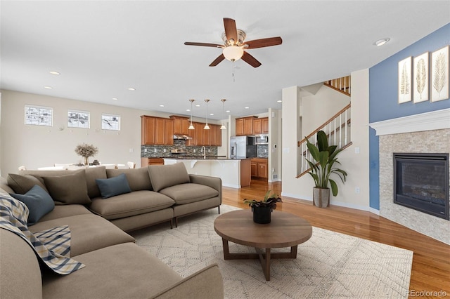 living room with light wood finished floors, recessed lighting, a glass covered fireplace, ceiling fan, and baseboards