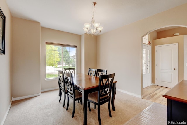 1864 Malibu Ct, Fort Lupton, CO 80621 - dining area with arched walkways, a chandelier, baseboards, and light carpet