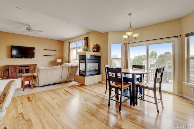 1864 Malibu Ct, Fort Lupton, CO 80621 - dining area featuring a multi sided fireplace, light wood-style flooring, a chandelier, a ceiling fan, and baseboards