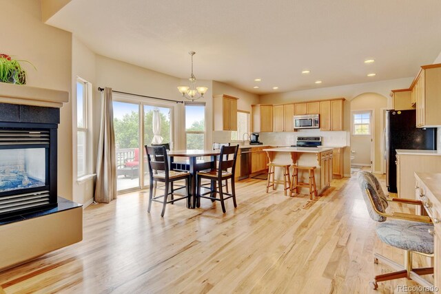 1864 Malibu Ct, Fort Lupton, CO 80621 - dining room featuring light wood-style flooring, a chandelier, a tiled fireplace, recessed lighting, and arched walkways