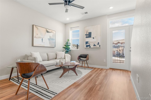 living area featuring plenty of natural light, baseboards, and light wood finished floors