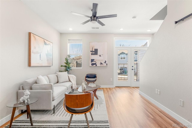 living area with a ceiling fan, visible vents, light wood finished floors, baseboards, and french doors