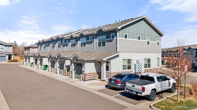 multi unit property featuring a residential view, board and batten siding, roof with shingles, and stone siding