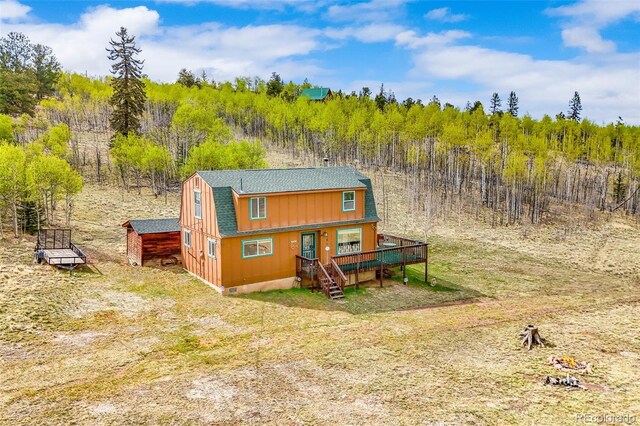 584 Old Squaw Rd, Como, CO 80432 - rear view of property with a gambrel roof, a view of trees, roof with shingles, and a wooden deck