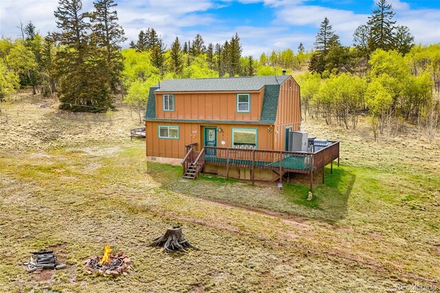 584 Old Squaw Rd, Como, CO 80432 - view of front of house with a gambrel roof, a deck, a fire pit, a shingled roof, and a front yard