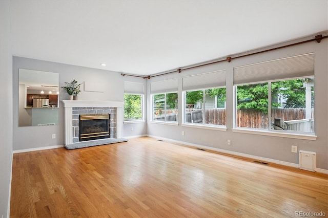 5721 S Jellison St, Littleton, CO 80123 - unfurnished living room featuring plenty of natural light, a stone fireplace, and wood finished floors