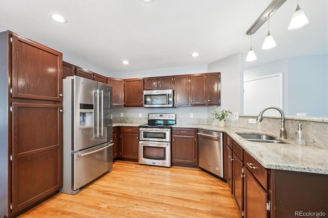 5721 S Jellison St, Littleton, CO 80123 - kitchen with stainless steel appliances, a peninsula, light wood-style floors, light stone counters, and pendant lighting