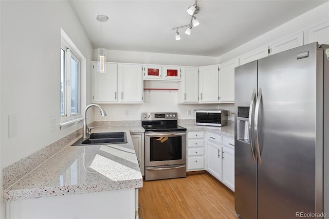 kitchen with white cabinets, hanging light fixtures, sink, and appliances with stainless steel finishes