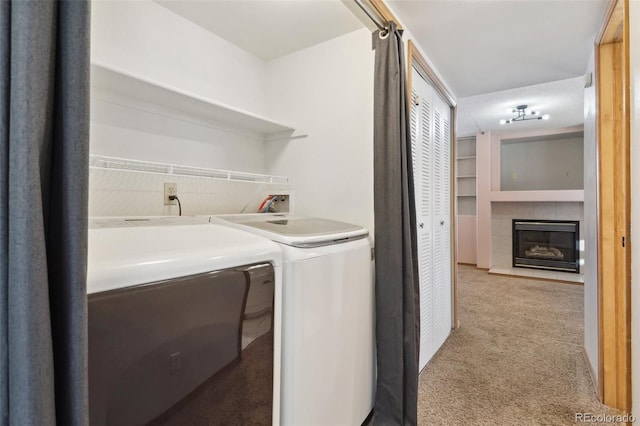 laundry room featuring washer and clothes dryer, light carpet, and a tiled fireplace